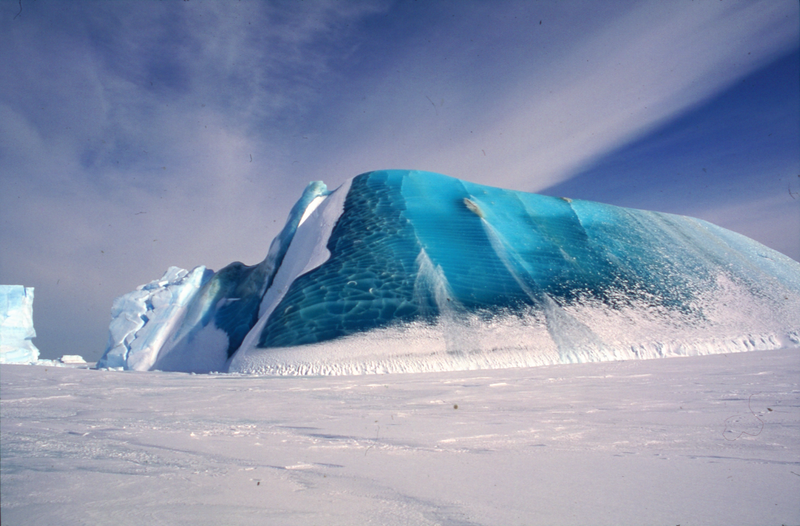 A partly capsized iceberg including deep-blue marine ice and white glacial ice.